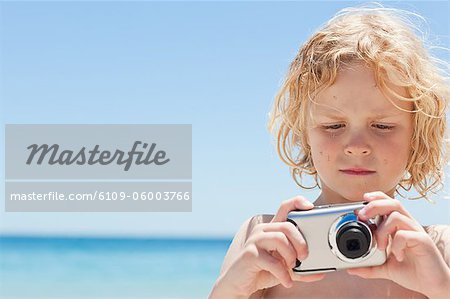 Petit garçon avec un appareil photo à la plage