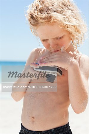 Petit garçon sur la plage de jeter un oeil à l'écran d'un appareil photo numérique