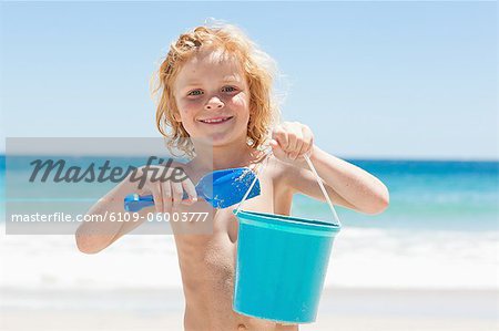 Little boy with a bucket and shovel on the beach