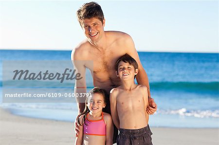 Père souriant sourire permanent avec ses petits enfants sur la plage