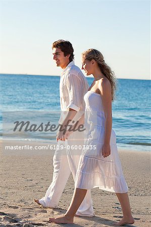 Vue latérale d'un jeune couple marchant au bord de la mer