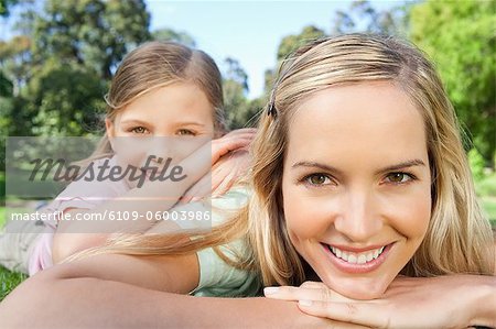 Une jeune fille souriante, reposant sur l'épaule de sa mère dans le parc