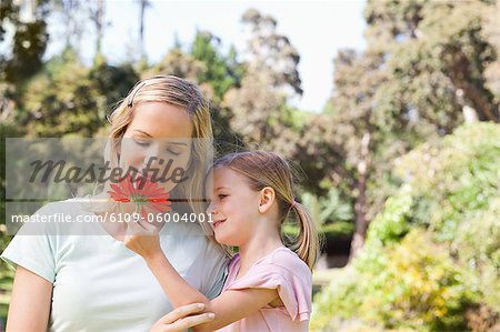 A mother looking at the pretty flower her daughter is holding