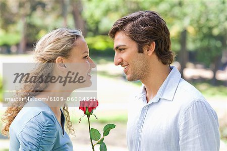 Side view of a young man offering a rose to his girlfriend