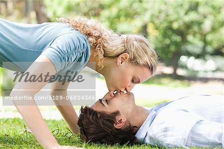 Side view of a young couple kissing on the grass