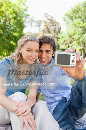 Sourire de jeune couple prendre des photos d'eux-mêmes dans le parc