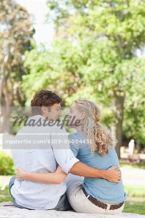 Vue arrière d'un jeune couple souriant assis dans le parc