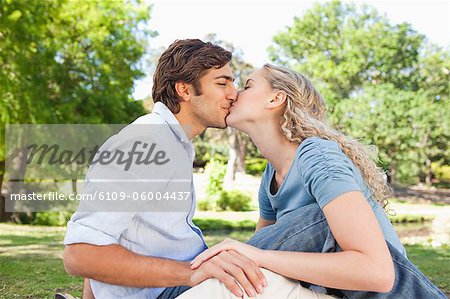 Vue latérale d'un jeune couple kssing sur la pelouse