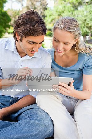 Jeune couple à l'aide d'une tablet PC dans le parc