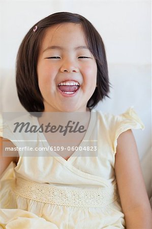 A close up portrait shot of a young girl as she sits on the couch while laughing,