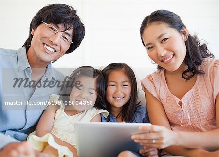 Eine glückliche Familie, einem Tablet PC und geradeaus schauen beim Lächeln