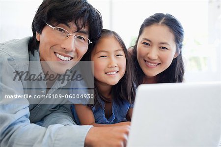 Parents and their daughter playing with tablet toghether as they sit on the couch