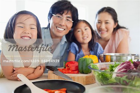 A salad on the table unprepared which will be made by the smiling family in front of it