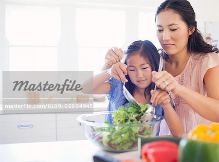 Une fille et sa mère à lancer une salade ensemble dans la cuisine