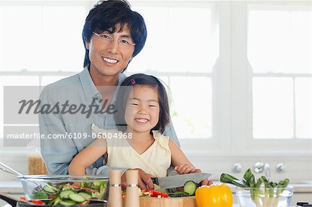A smiling father and daughter sitting in the kitchen as they prepare food for dinner