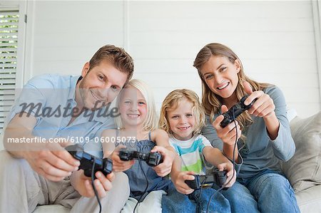 Eine lächelnde Familie selbst zu genießen, wie sie Spiele spielen, während sie auf der Couch sitzen