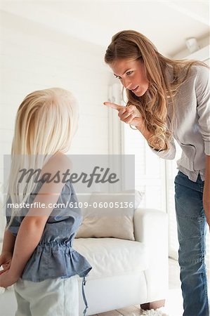 A mother sternly points at her daughter as she corrects her for doing something bad
