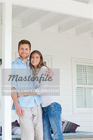 A smiling man and woman looking up from the porch outside