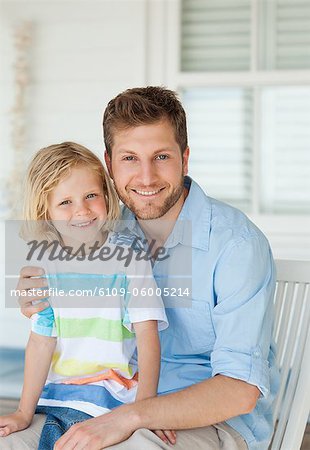 A smiling father and son sit on the seat together as the look straight ahead
