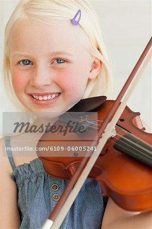 Une jeune fille joue du violon dans ses mains comme elle sourit