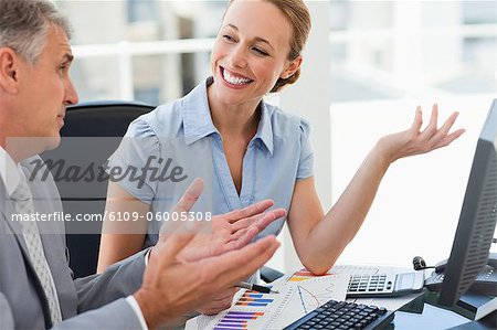 Smiling employee explaining figures to her boss in a bright office