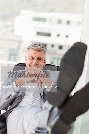 Portrait d'un patron avec les pieds sur son bureau dans un bureau lumineux