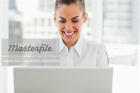 Femme souriante aux cheveux crépuse, travaillant avec un ordinateur portable dans un bureau lumineux