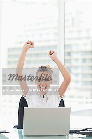 Très heureuse femme d'affaires tannée, lever les bras dans un bureau lumineux