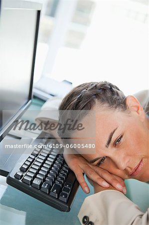Frau mit Zopf-Kopf auf der Tastatur in einem hellen Büro