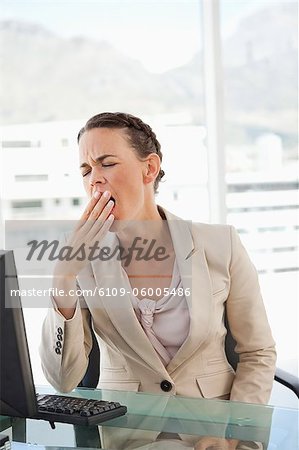 Femme d'affaires avec des tresses bâillement dans un bureau lumineux