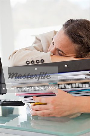 Businesswoman sleeping on a lot of files in a bright office