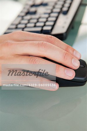 Gros plan de la main de l'homme, déplacer une souris sur un bureau en verre