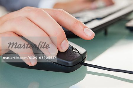 Close-up of man hand clicking with a mouse on a glass desk