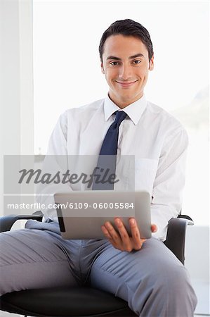 Portrait of a businessman using a touchpad while sitting in a bright office