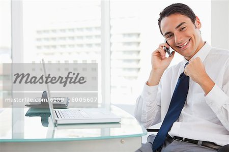 Happy businessman receiving good news by phone in a bright office