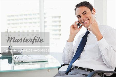 Portrait of a businessman receiving good news by phone in a bright office