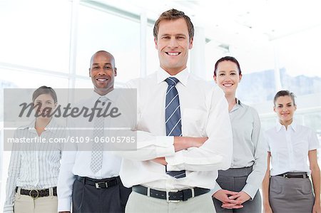Homme d'affaires souriant avec ses bras croisés avec son équipe