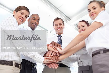 Lächelnd junger Salesteam setzen ihre Hände zusammen für eine Geste der Teamarbeit