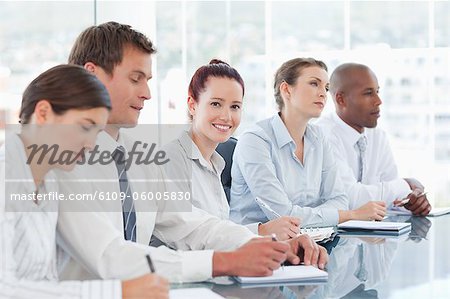 Smiling young saleswoman sitting in a meeting with her colleagues