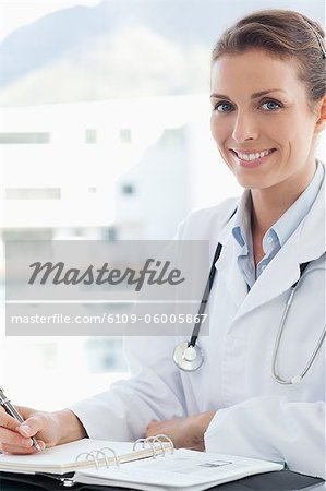 Smiling female doctor with pen and pocket calendar