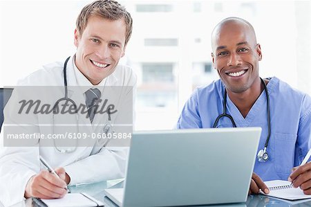 Smiling doctors together with laptop