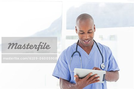 Médecin de sexe masculin souriant à l'aide de tablet PC