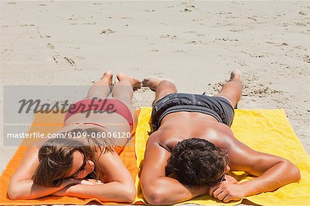 High angle-shot of a tanned couple sleeping on the beach