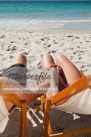 Close-up on the hands of a couple in deck chair in front of the sea
