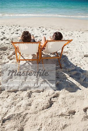 Rear view of a couple in folding chair in front of the sea