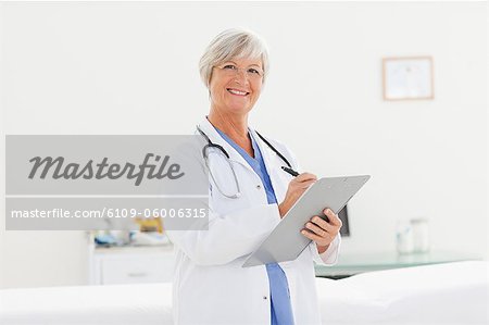 Smiling mature doctor with clipboard and pen