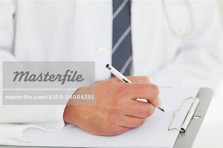 Gros plan de médecins masculins main écrit dans un presse-papiers