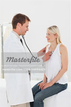 Smiling male doctor taking his patients heart beat