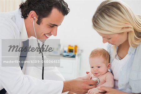 Smiling male doctor measuring little babys heart beat