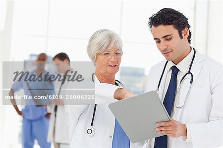 Mature doctor explaining patients record to her young colleague